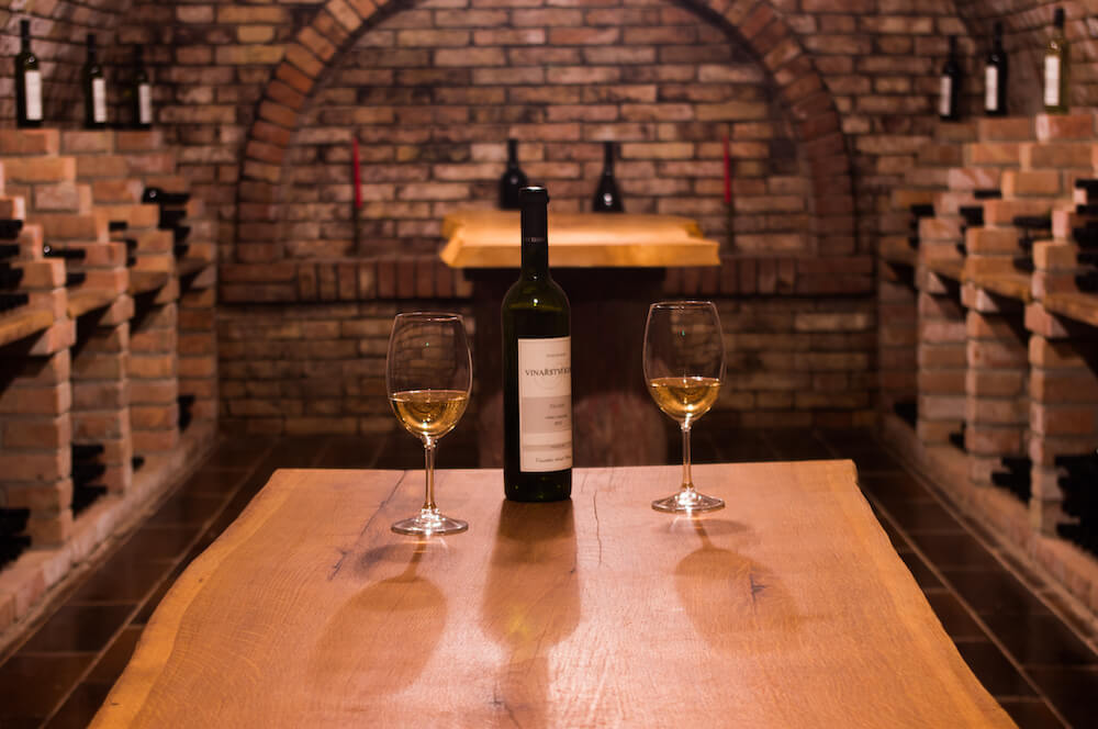 Lahev a skleničky s vínem ve vinném sklepě